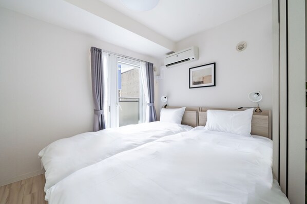 A modern hotel room with a large bed, a window with curtains, an air conditioning unit, and a framed picture on the wall. - EVARIA (Sapporo)