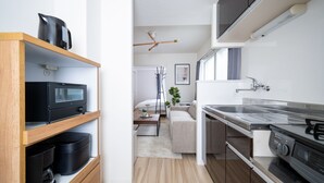 A modern kitchen with a microwave, stove, and wooden shelves. - EVARIA (Sapporo)