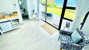 A modern living room with a large sliding glass door leading to a balcony with a view of the sea.