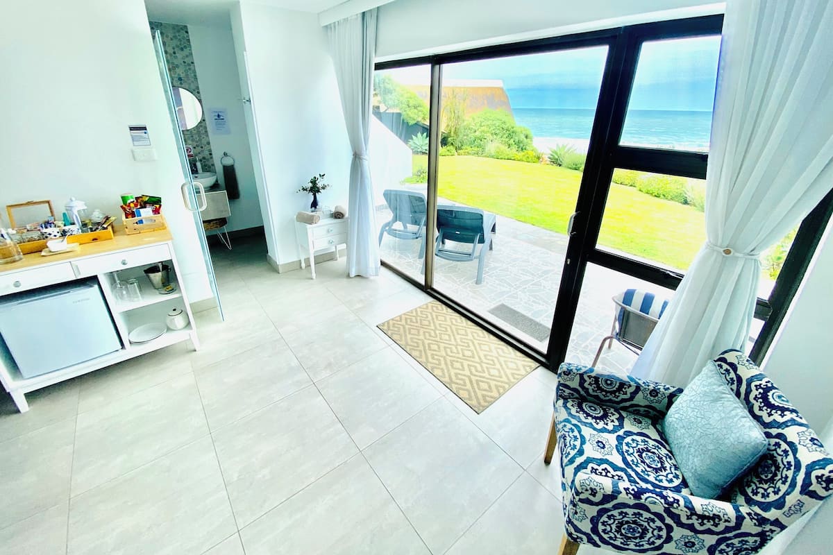 Un salón moderno con un gran ventanal corredero que da a un balcón con vistas al mar.