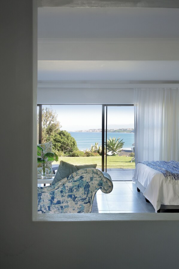 A bedroom with a large sliding glass door leading to a balcony with a view of the sea. - Mykonos Luxury Guest House (Saint Francis Bay)