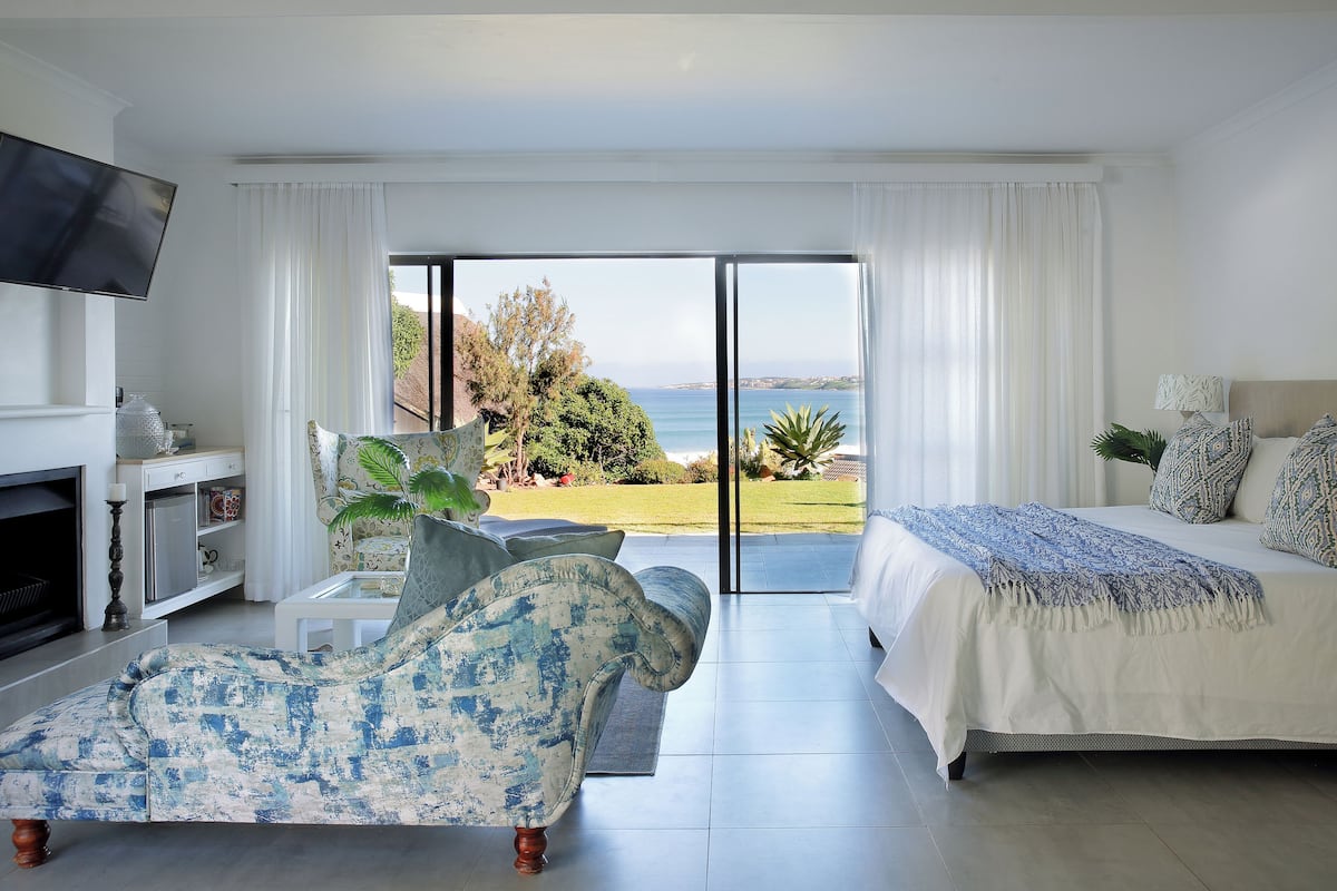 Un dormitorio con una cama grande, un sofá, un televisor y vista al mar.