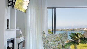 A modern living room with a fireplace, a sofa, a coffee table, and a view of the sea.