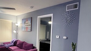 A modern living room with a sectional sofa, a green rug, and a decorative wall piece. - Welcome To Your Comfy GetAway! (Dallas)