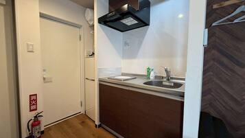 Een koelkast, een magnetron, een kookplaat, kookgerei, borden en bestek