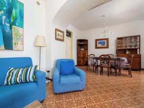 Una sala de estar con un sofá azul, una mesa de comedor con sillas, un mueble de madera y un piso con diseño.