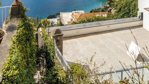 A coastal view with a clear sky, a rocky cliff, and a body of water. - Scorcio d'Oltremare (Positano)