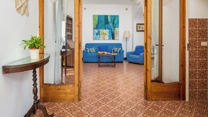 An interior with a wooden archway leading to a living area with a blue sofa, a coffee table, and a painting on the wall. - Scorcio d'Oltremare (Positano)