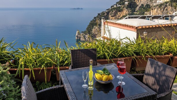 A table with a glass of red wine, a glass of white wine, and a bowl of lemons on a balcony overlooking the sea. - Scorcio d'Oltremare (Positano)