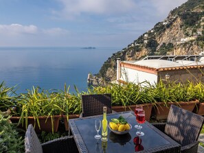 A table with a glass of red wine, a glass of white wine, and a bowl of lemons on a balcony overlooking the sea. - Scorcio d'Oltremare (Positano)