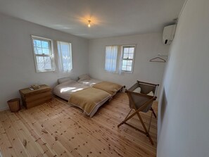Un dormitorio con dos camas, un aparador de madera, una mesita y una ventana.