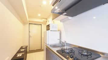 Een koelkast, een magnetron, een kookplaat, kookgerei, borden en bestek