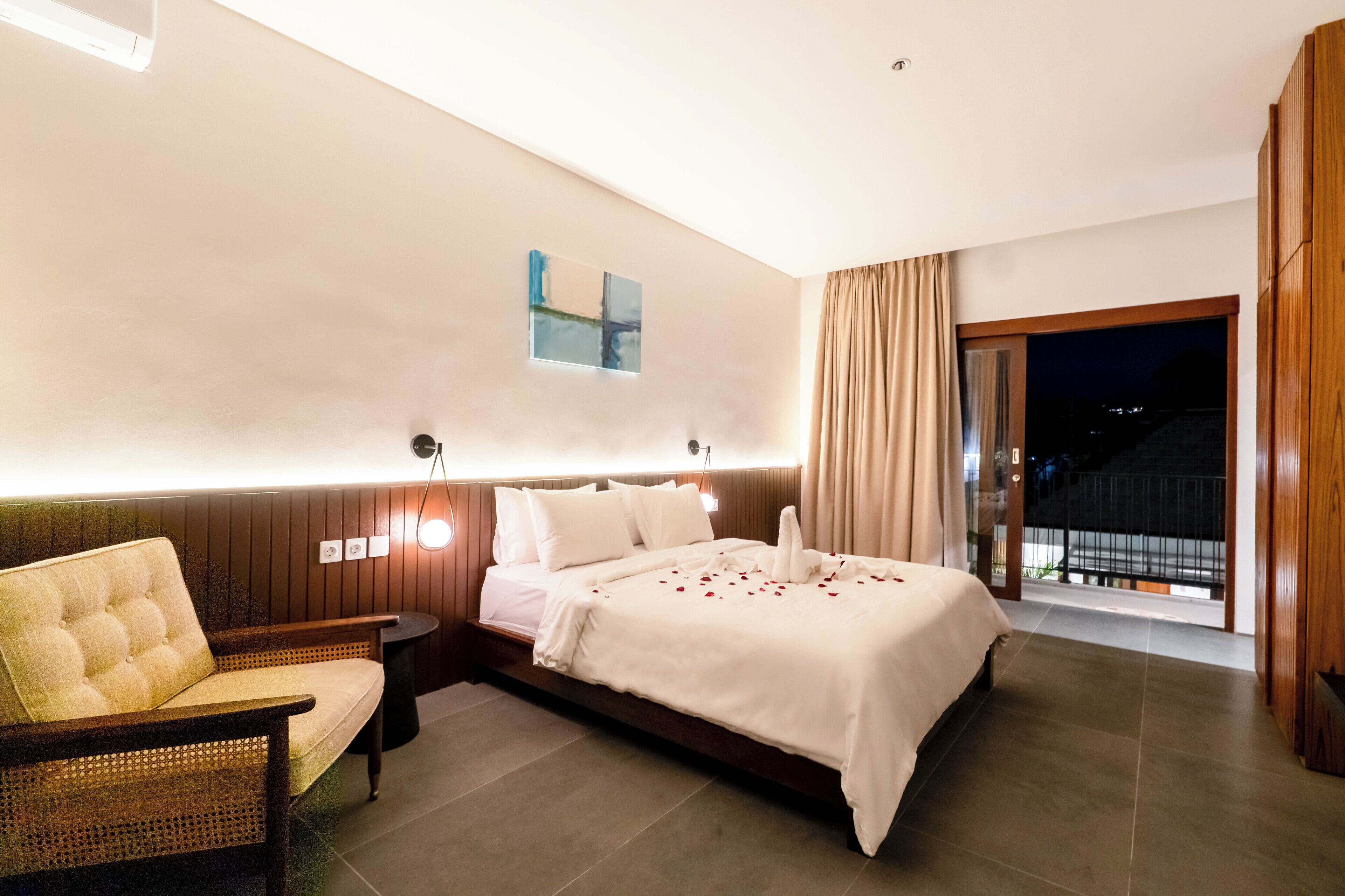 Une chambre d’hôtel avec un lit, un canapé, une lampe fixée au mur et une vue sur l’extérieur.