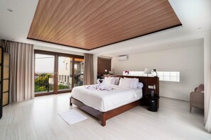 Een moderne hotelkamer met een groot bed, een houten plafond, een balkon met gordijnen en uitzicht op het omliggende landschap.
