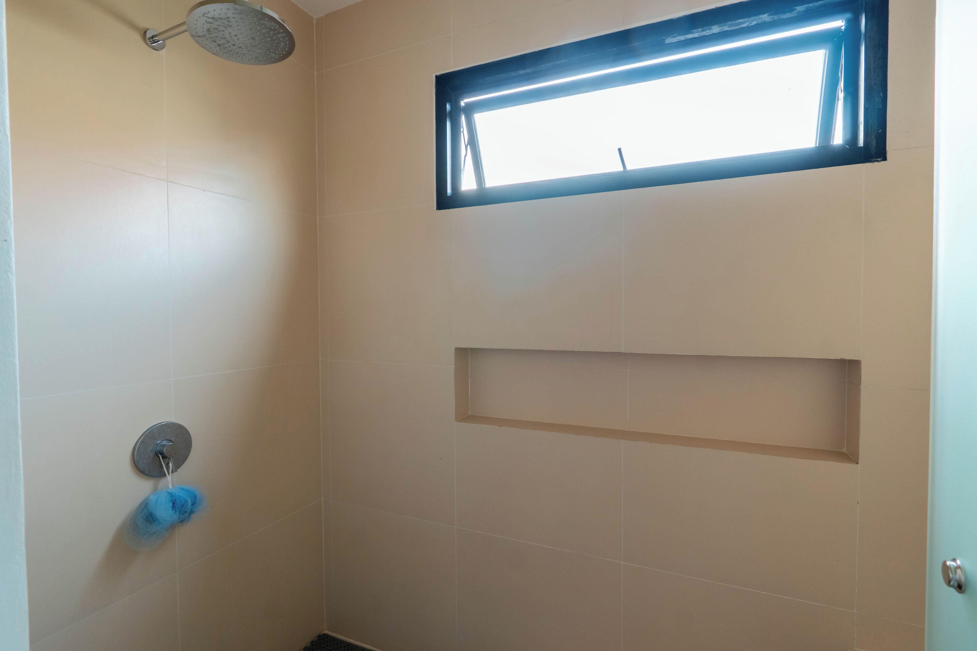 A bathroom with a shower, a small window, and a towel rack.