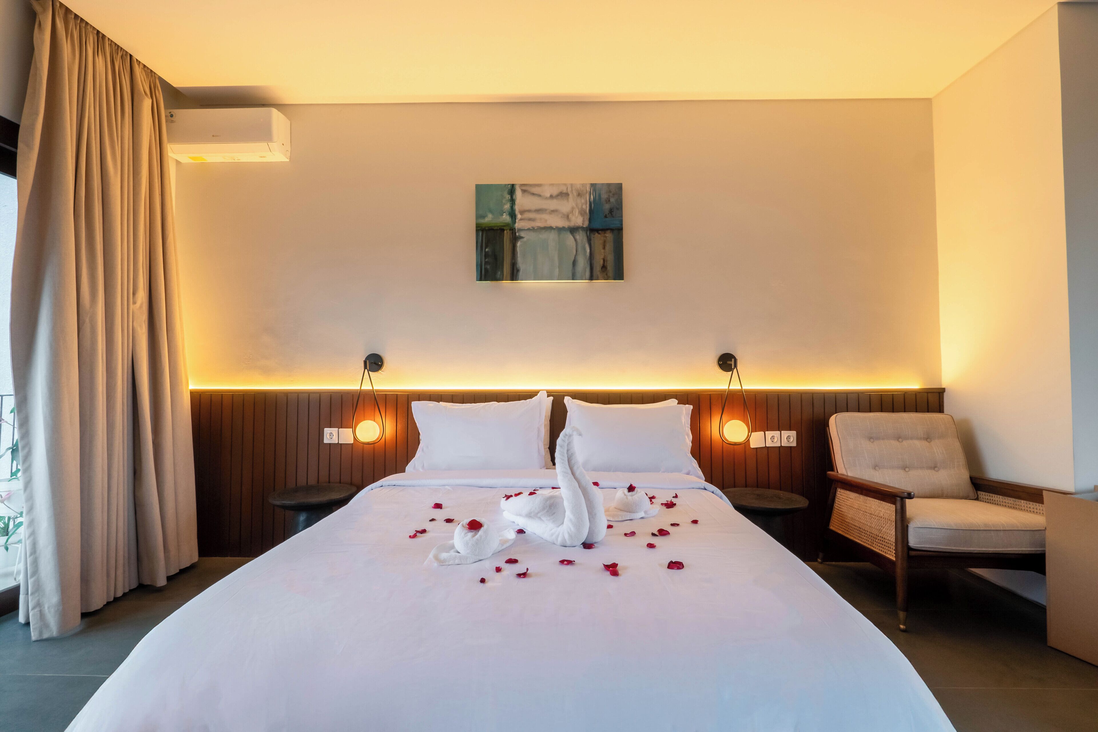 A hotel room with a large bed, two bedside tables, a chair, and a painting on the wall.