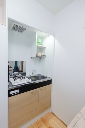 Een koelkast, een magnetron, een kookplaat, kookgerei, borden en bestek