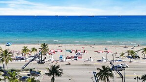 Una playa con palmeras, sombrillas y un camino que lleva a la playa.