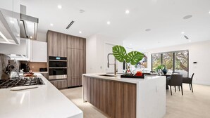 Una cocina moderna con una isla central, electrodomésticos integrados y un comedor con vistas.