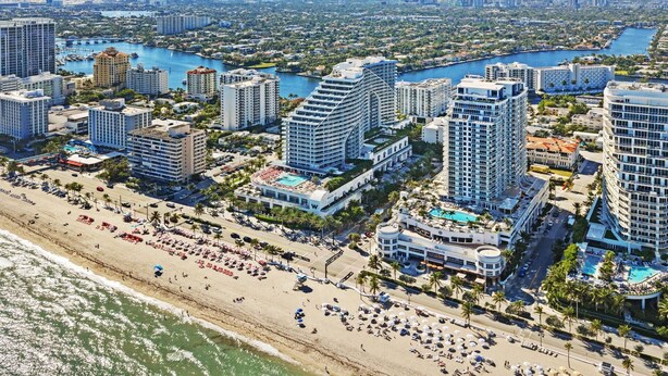 Un paisaje urbano costero con hoteles de gran altura, una playa y un puerto deportivo.