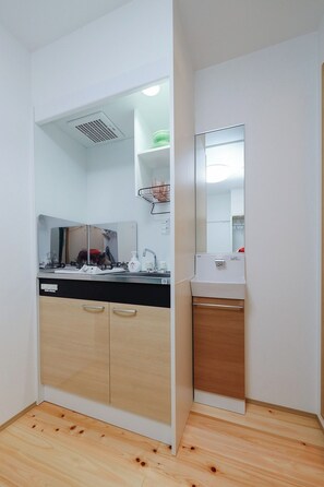 Een koelkast, een magnetron, een kookplaat, kookgerei, borden en bestek