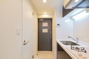 Een koelkast, een magnetron, een kookplaat, kookgerei, borden en bestek