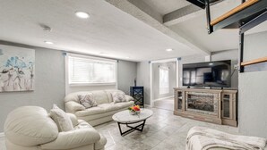 Un salón con un sofá color beige, una mesa redonda y una chimenea.