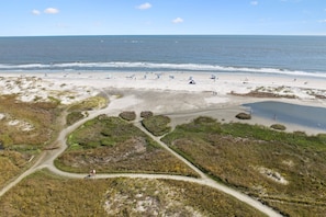 A beach with a path leading to the water, sandy areas, and some vegetation.