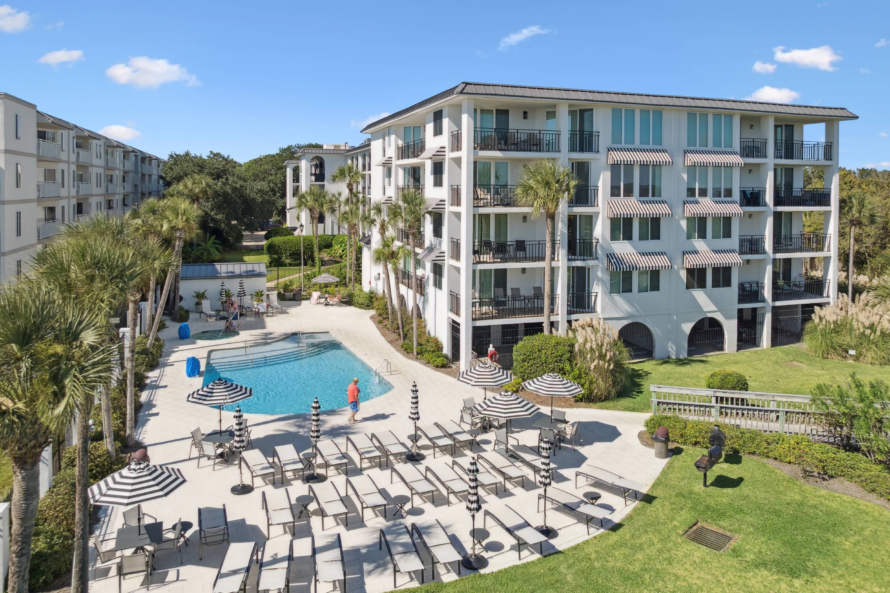 Un hôtel doté d’une piscine, d’un espace extérieur aménagé et d’un bâtiment à plusieurs étages avec des balcons.