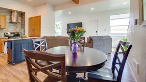 A modern kitchen with wooden cabinets, a built-in stove, and a dining area with a round table and chairs. - 1 Mi to Dtwn Coos Bay: Sleek Apt w/ Deck & Views! (Coos Bay)