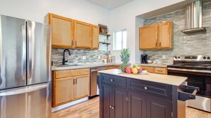 A modern kitchen with stainless steel appliances, wooden cabinets, and a tiled backsplash. - 1 Mi to Dtwn Coos Bay: Sleek Apt w/ Deck & Views! (Coos Bay)