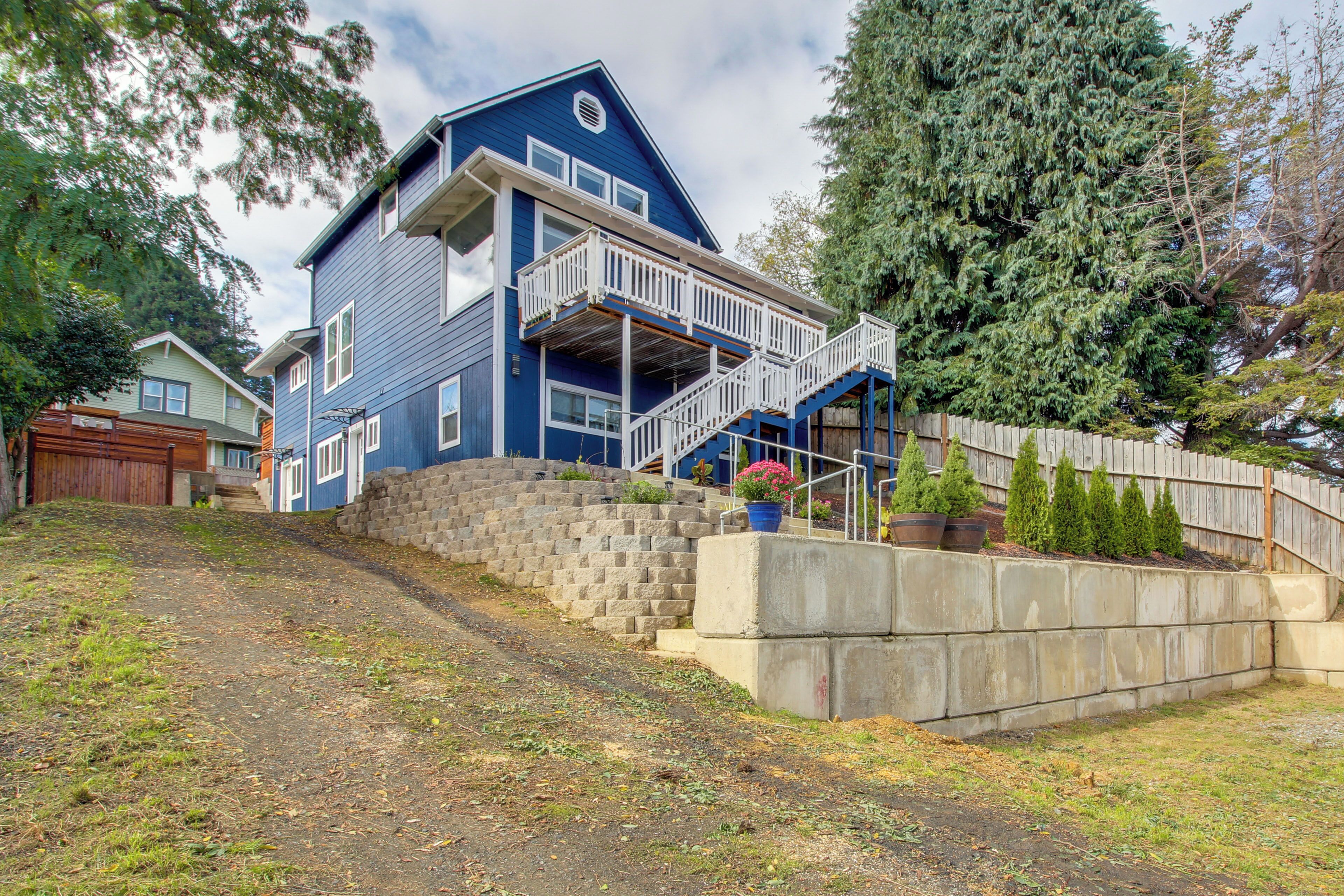 A two-story house with a blue exterior, a front porch, and a staircase leading to a balcony.