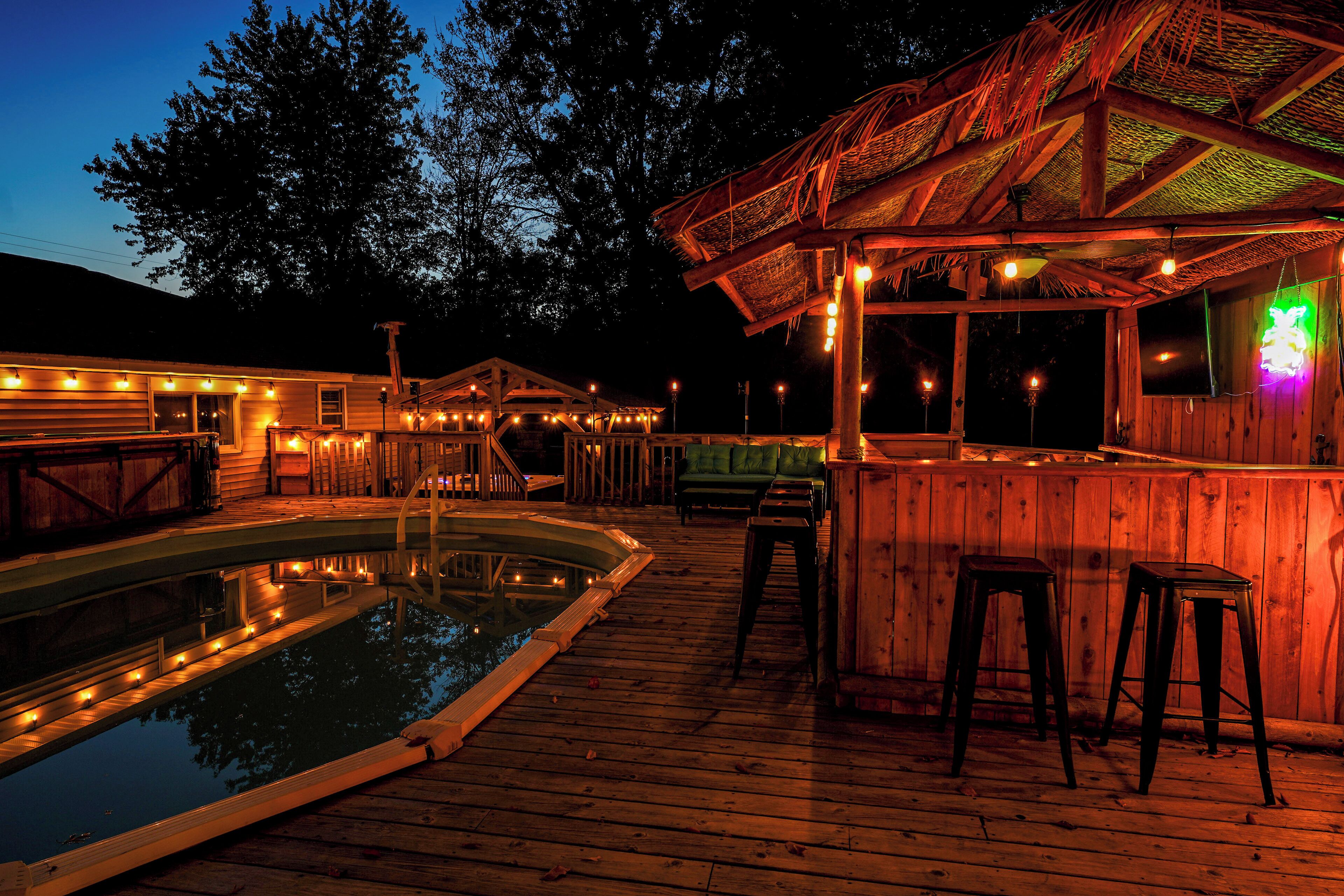 A wooden deck with a pool, bar area, and seating.