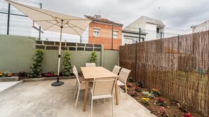 A patio with a wooden table and chairs, a large umbrella, and a bamboo fence.