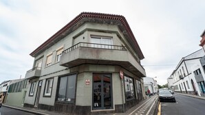 A corner building with a balcony, large windows, and a door with a sign.