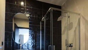 A modern bathroom with a glass-enclosed shower, a white sink, and a large mirror.