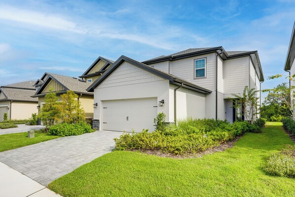 A modern residential building with a garage, well-maintained lawn, and a clear sky. - Disney World Group Getaway in Reunion Resort! (Kissimmee)