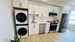 Een moderne keuken met witte kasten, een LG wasmachine, een vaatwasser, een magnetron en een roestvrijstalen koelkast.