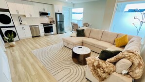 Een moderne woonkamer met een beige bank, een bijzettafeltje en een gestreept tapijt.