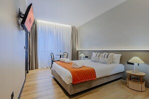 Une chambre d’hôtel équipée d’un lit, d’une table de chevet, d’une lampe et d’un téléviseur fixé au mur.