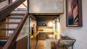 A compact kitchen with a built-in refrigerator, microwave, and a small dining area with a bench and a bowl. - GuestReady - Classic prestige in Costa da Caparica (Costa da Caparica)