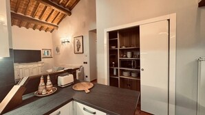 A modern kitchen with a built-in oven, microwave, and a wooden dining table. - City / Village Apartment in Cortona with 2 bedrooms sleeps 4 (Cortona)