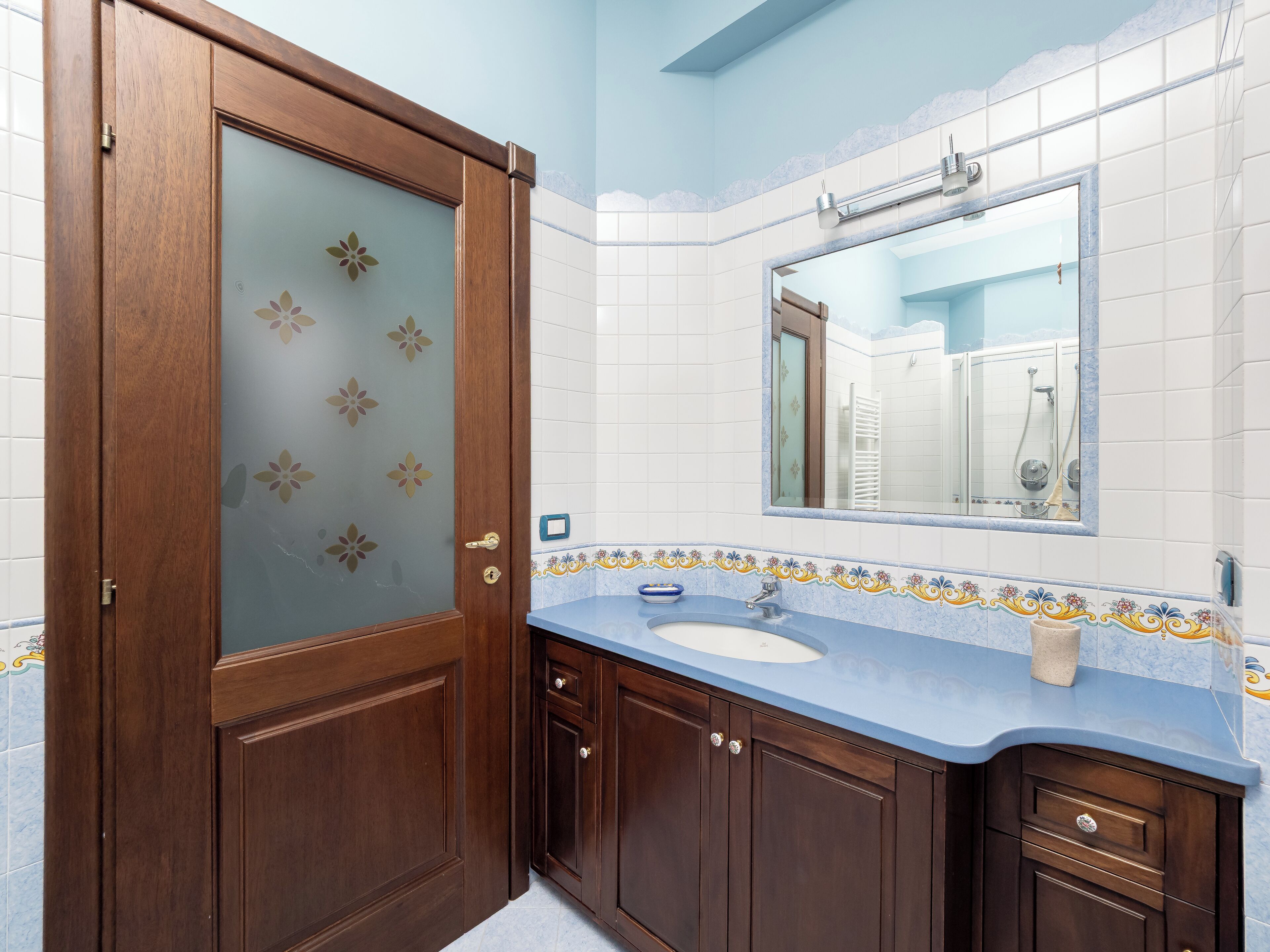 Un bagno con una porta in legno, un lavandino e uno specchio.