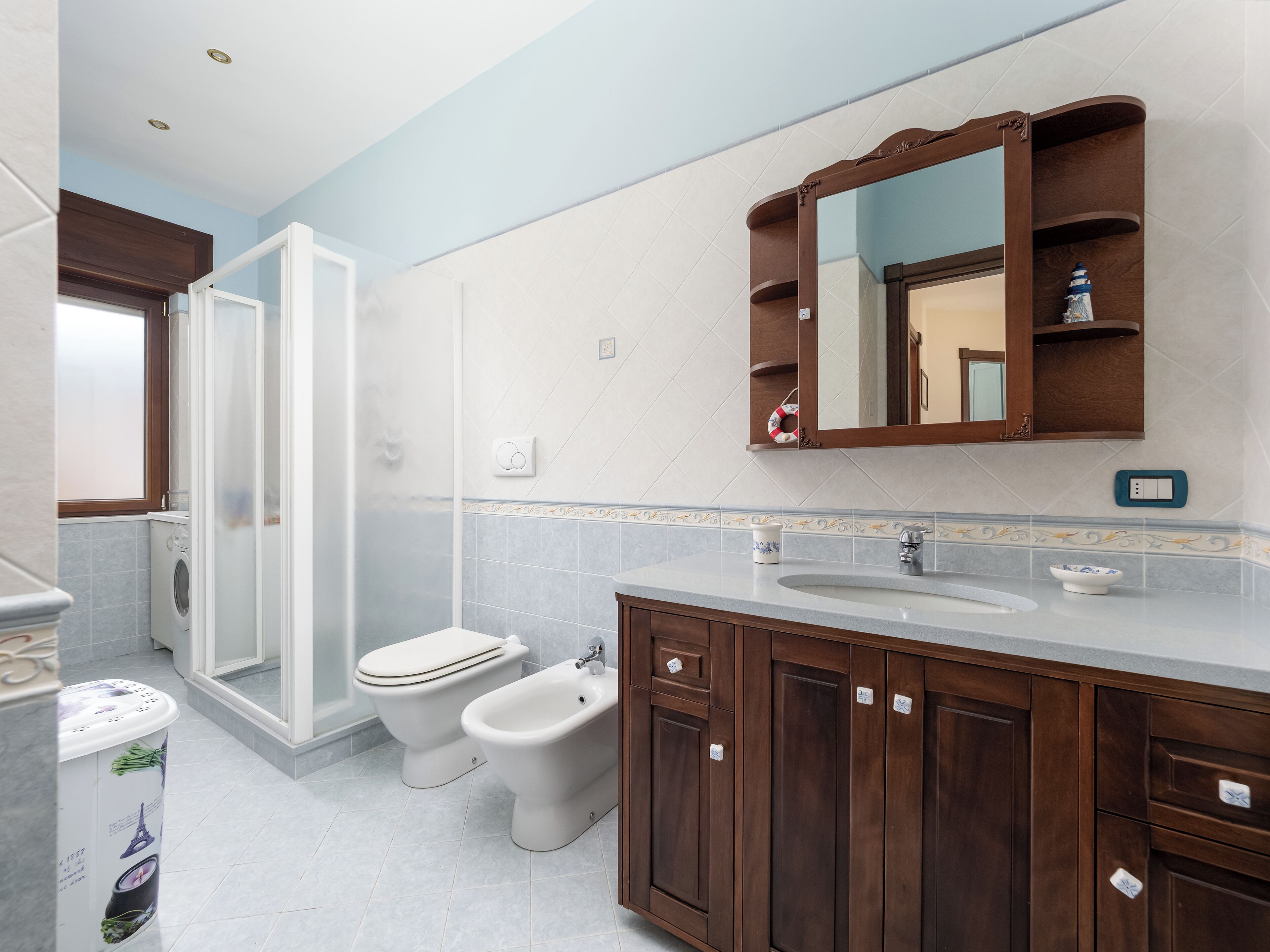 A modern bathroom with a shower, toilet, bidet, and vanity.