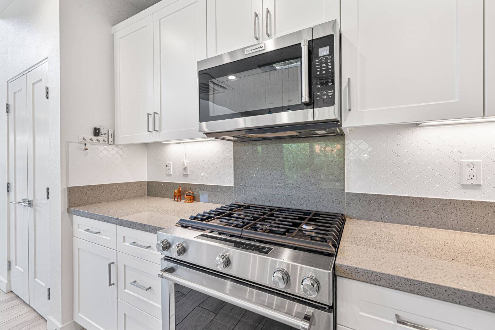 A modern kitchen with white cabinetry, a stainless steel stove, and a microwave.