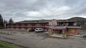 Un motel con varias habitaciones, una pequeña oficina y un área de estacionamiento.