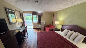 Una habitación de hotel con cama, escritorio, televisor, ventana y puerta.