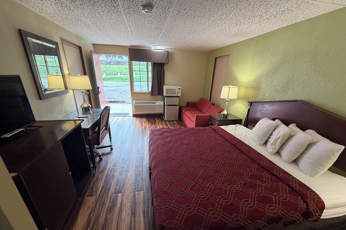 Een hotelkamer met een bed, een bureau, een televisie, een raam en een deur.
