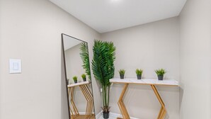 Een badkamer met een spiegel, een houten wastafelmeubel en een potplant.