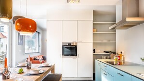 Une cuisine moderne avec des armoires blanches, un four encastré et un plan de travail bleu.